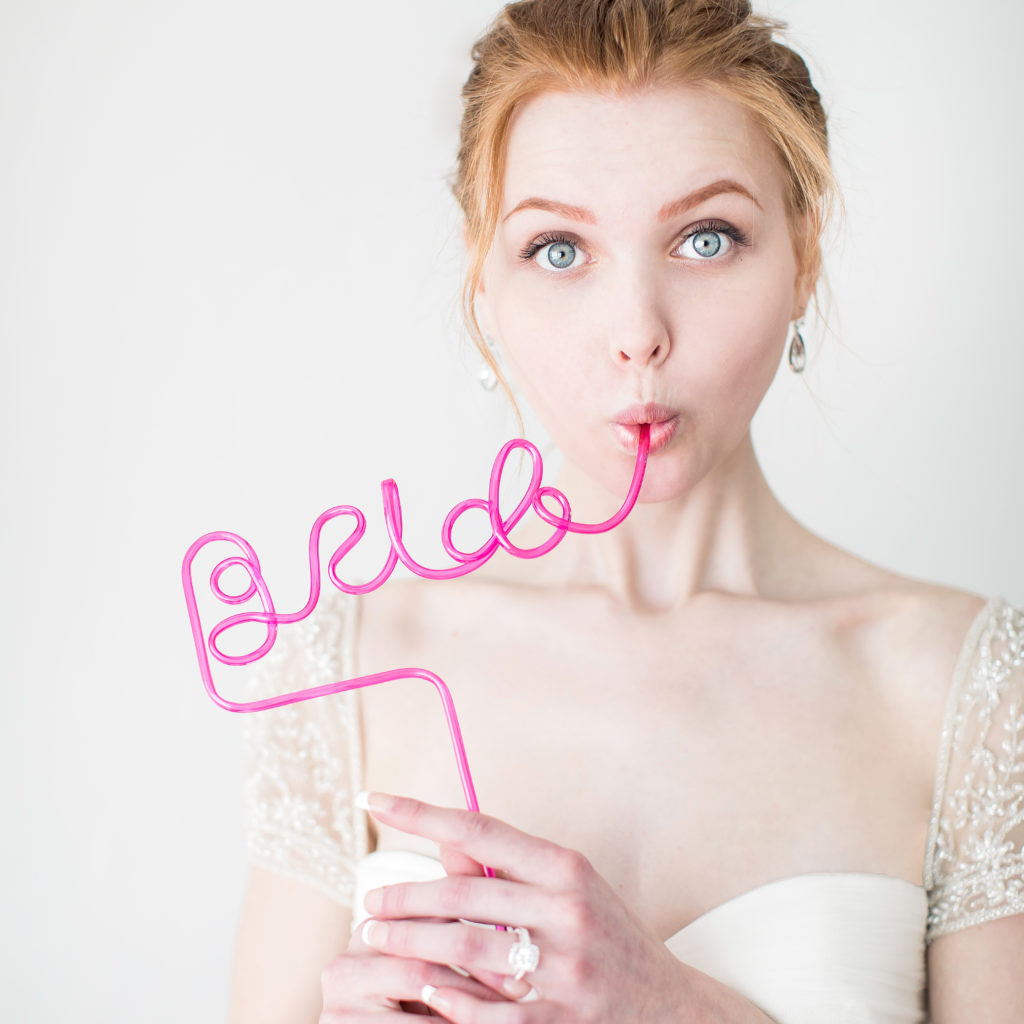 Bride drinking from a pink straw that spells the word bride acting surprised