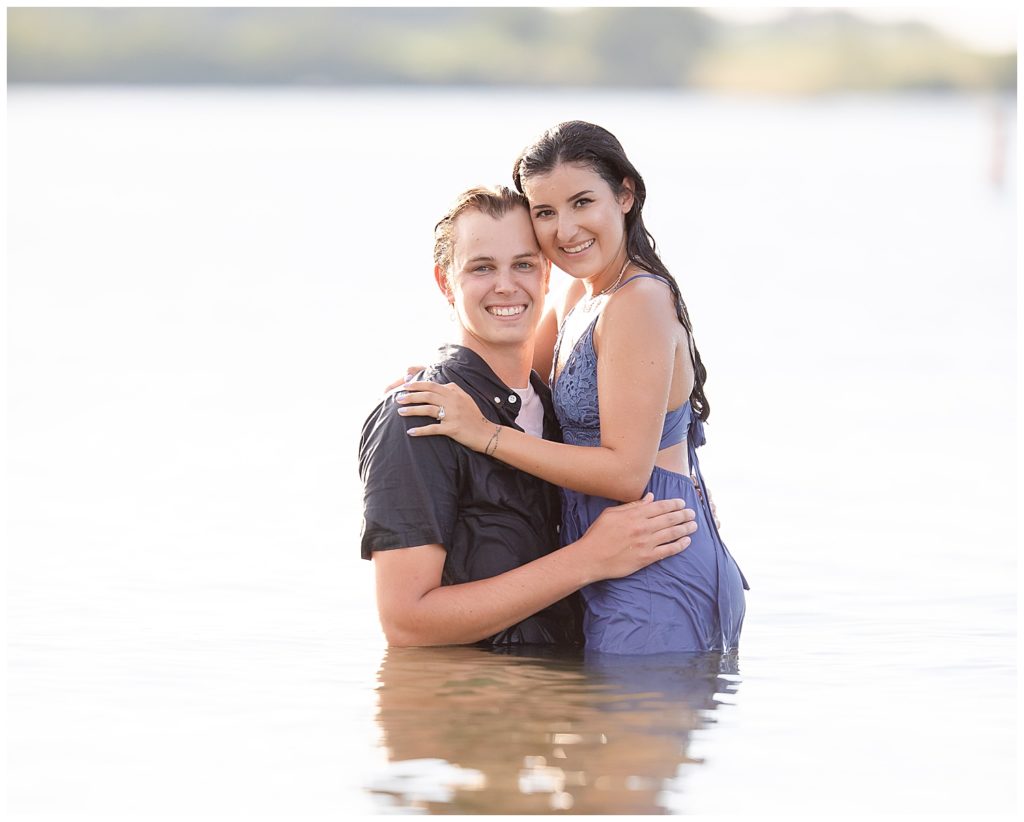Engaged couple smiling at the camera at Wall Lake, South Dakota during engagement session at sunset