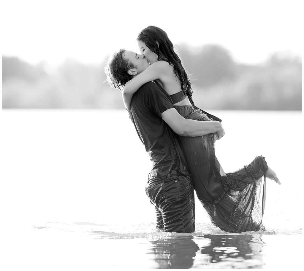 Black and white photo of Engaged couple dancing and kissing in Wall Lake, South Dakota during engagement session at sunset